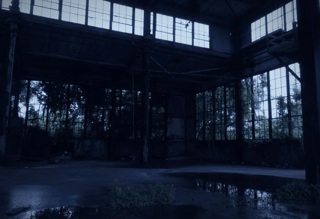 Drone aerial by CXIX: an abandoned industrial building with large broken windows and overgrown plants inside, with a dark and neglected atmosphere.