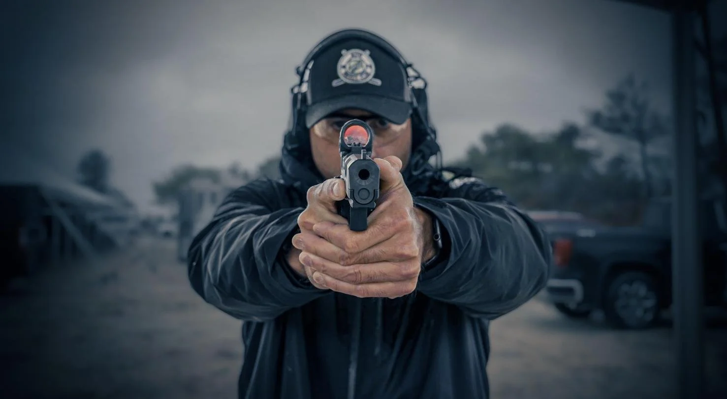 Officer aiming a red dot equipped pistol at the camera, tactical photography by CXIX Creative Group