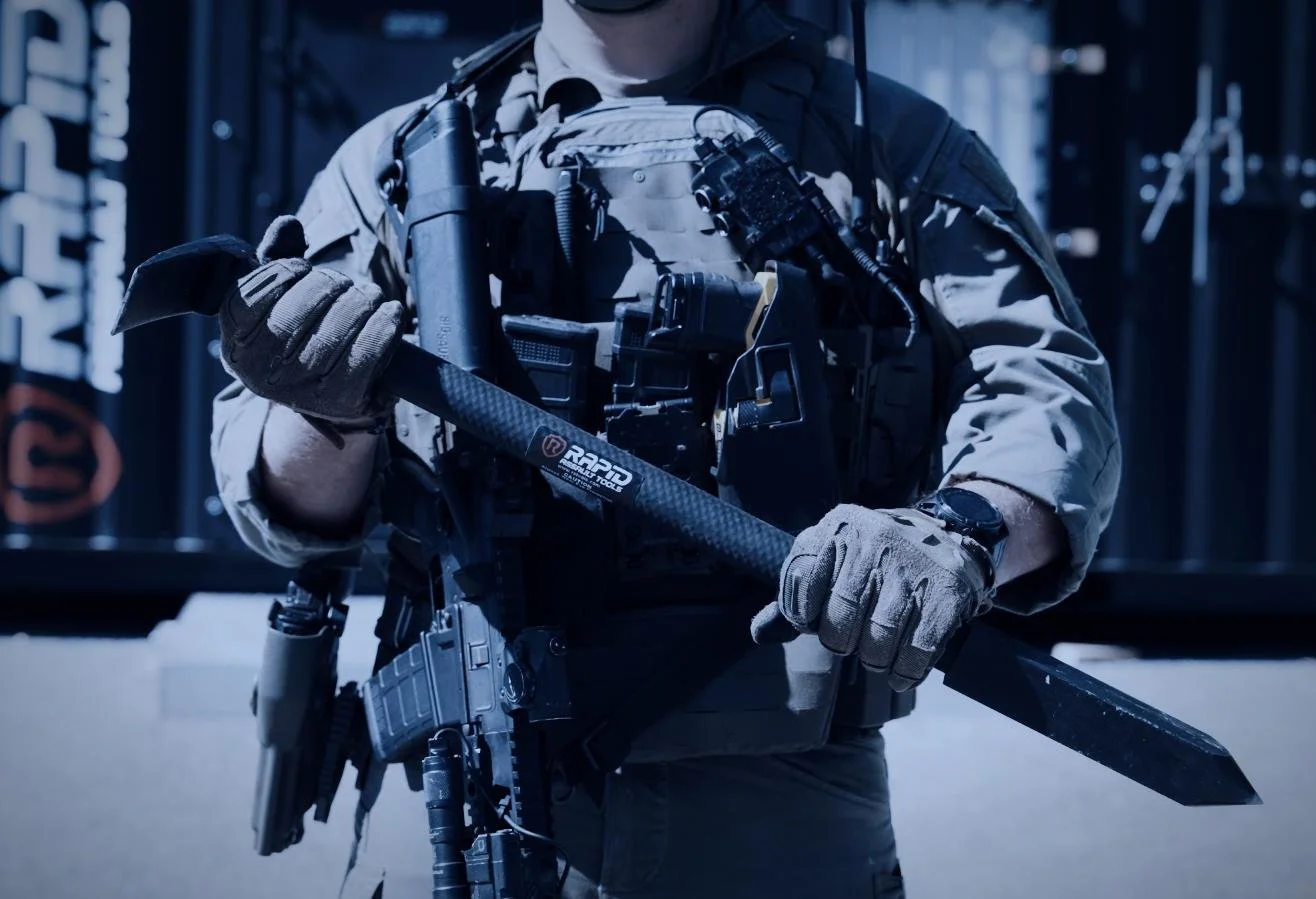 Rapid Assault Tools shoot by CXIX: a soldier wearing tactical gear, holding an axe and a firearm, in front of a shipping container.