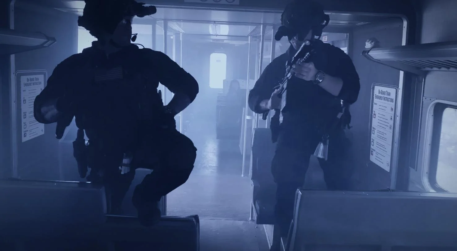 Long Island SWAT Challenge, shot by CXIX: two military personnel in tactical gear on a bus, one holding a rifle, with foggy or smoky atmosphere.