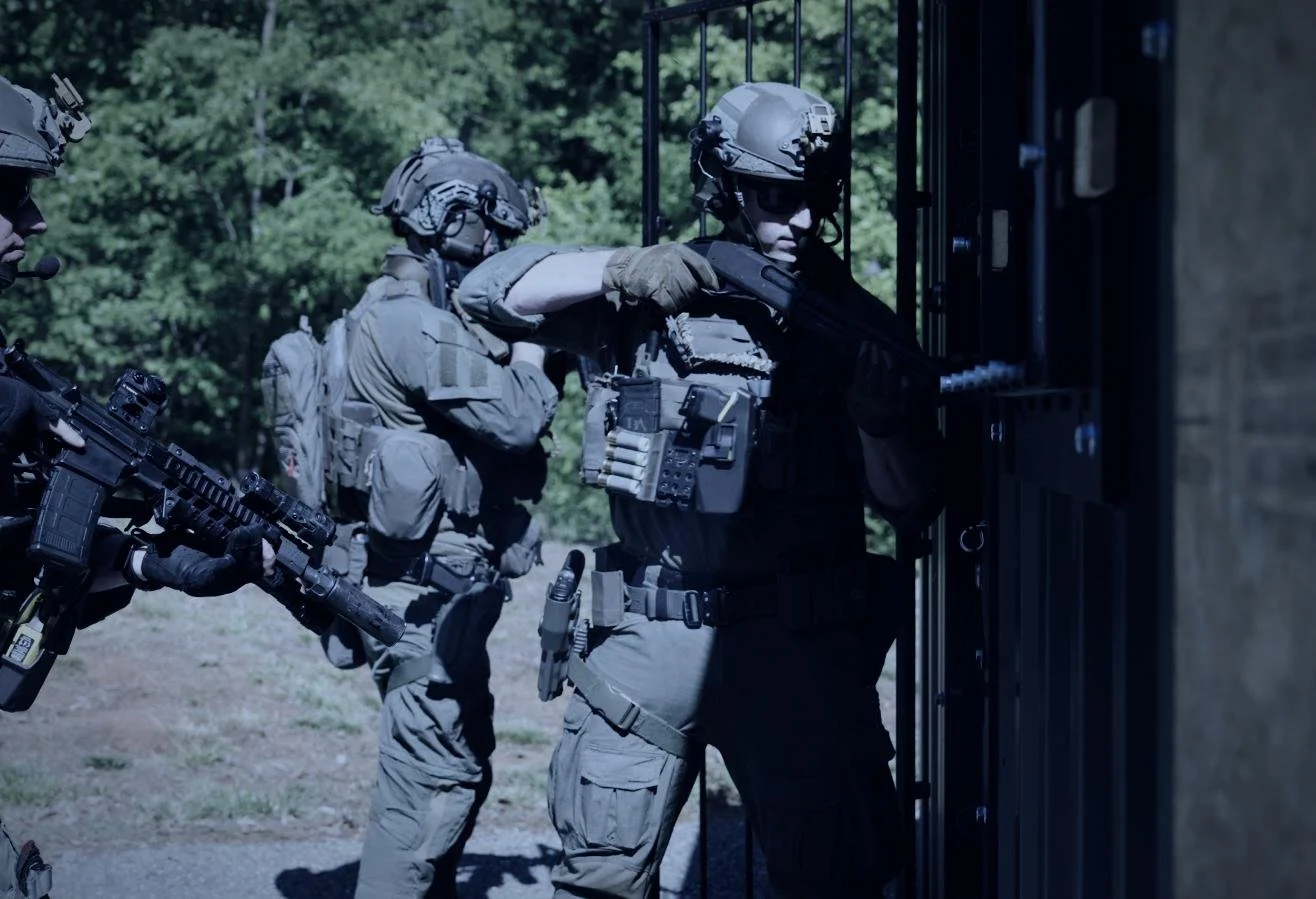 Rapid Assault Tools shoot by CXIX: soldiers in tactical gear practicing building entry skills outside in a wooded area.