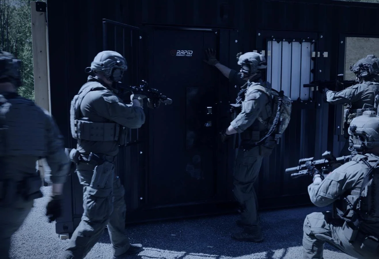 Rapid Assault Tools shoot by CXIX: military police team in tactical gear using weapons outside a dark-colored metal vault or safe.