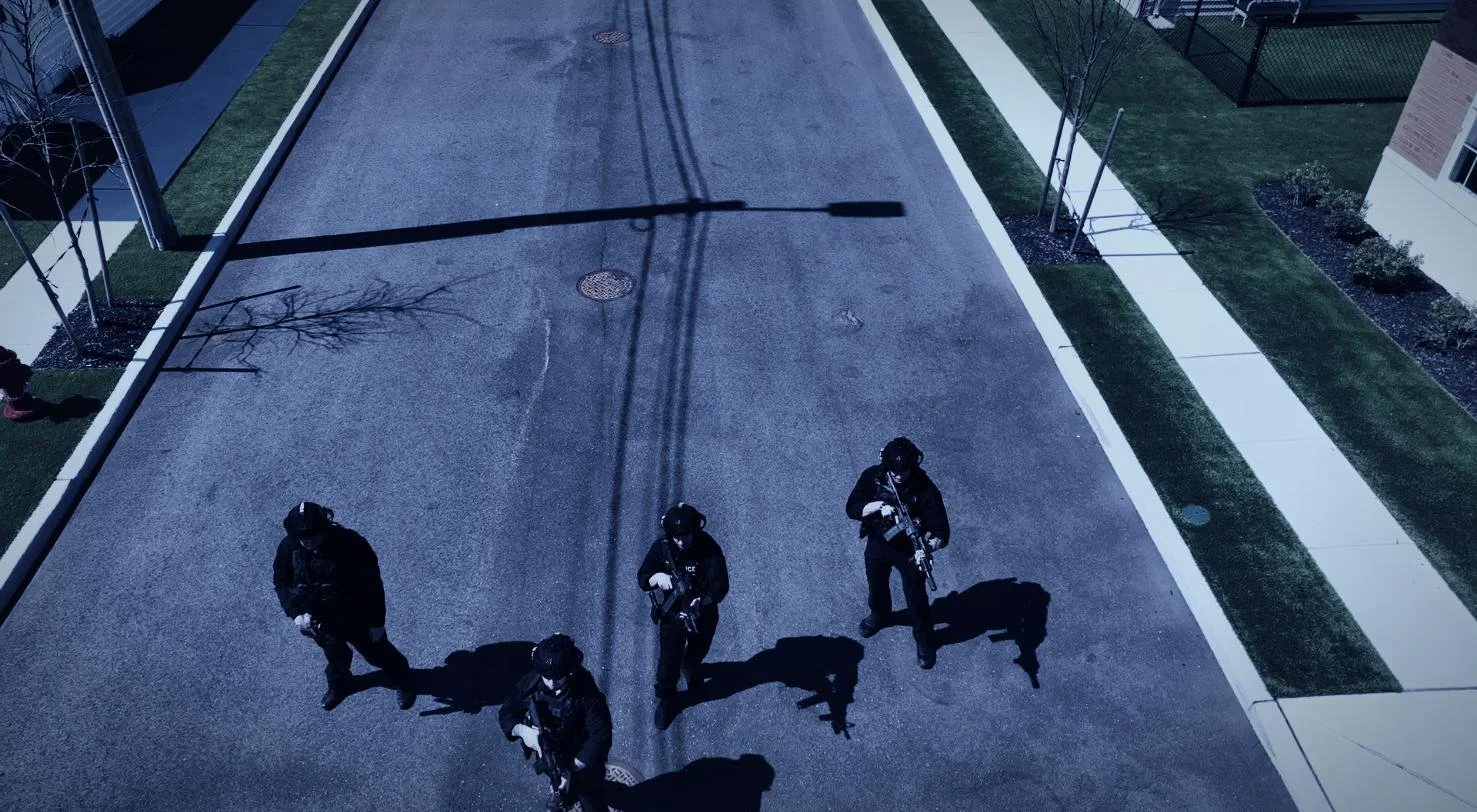 Long Island SWAT Challenge, shot by CXIX: four police officers standing on a street in a residential neighborhood at night, seen from above. Shadows of utility poles and trees are cast on the pavement.