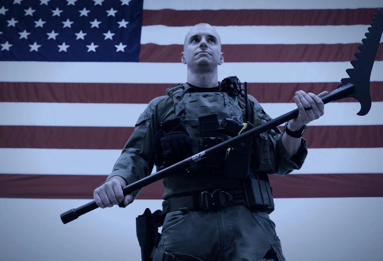 Rapid Assault Tools shoot by CXIX: a soldier in military gear holding a large black weapon in front of an American flag.