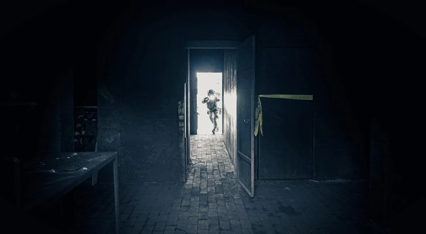 Long Island SWAT Challenge, shot by CXIX: person running through an open doorway from a dark room into a brightly lit outside area.