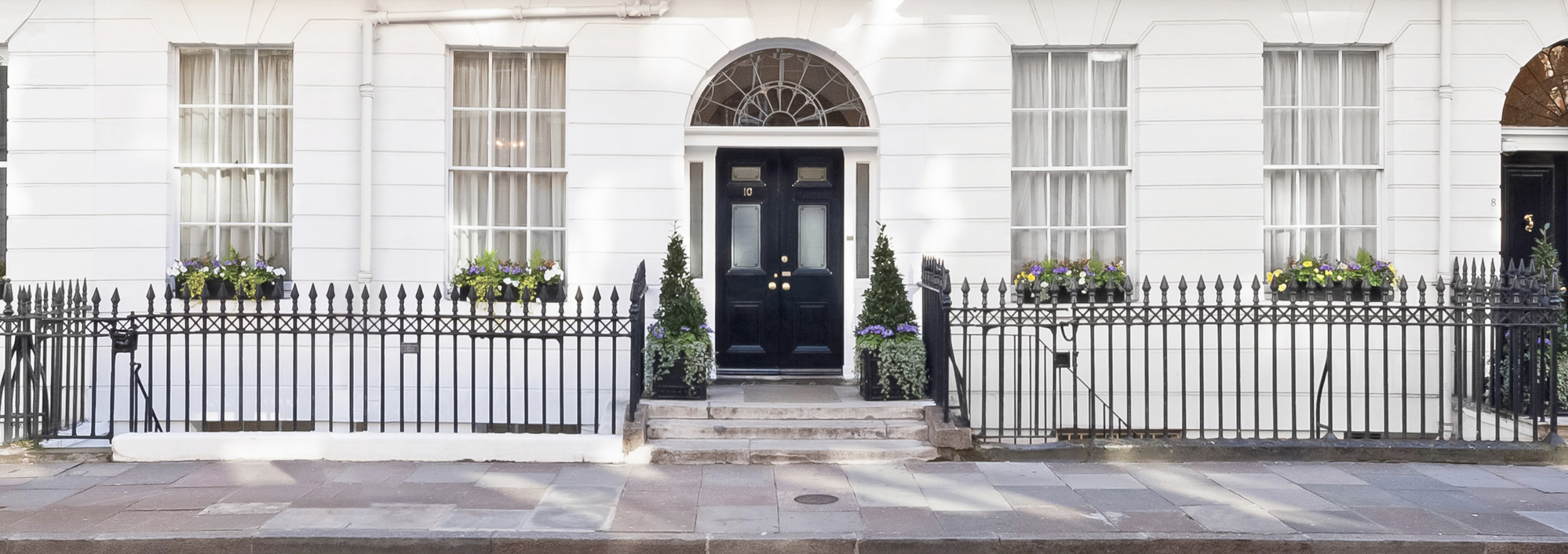 View of modern skyscrapers and classic brick buildings under a cloudy sky in an urban setting.