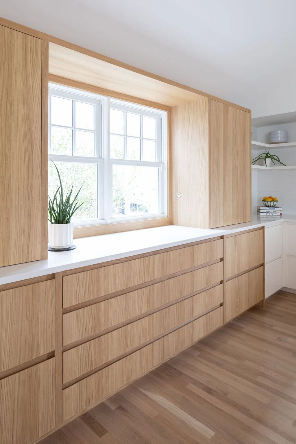 White oak kitchen cabinetry and integrated window surround with clean modern detailing.