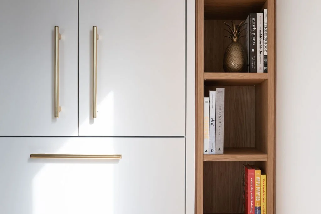 Detail of aged brass cabinet hardware and open white oak shelving.