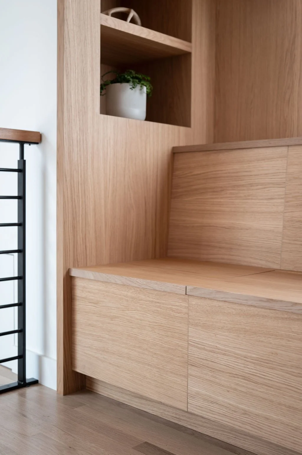 Close view of white oak banquette seating and built-in shelving detail.