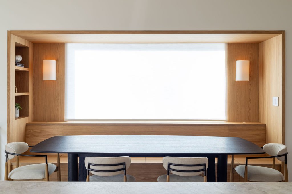 Custom white oak banquette seating framed around dining table with integrated wall sconces.