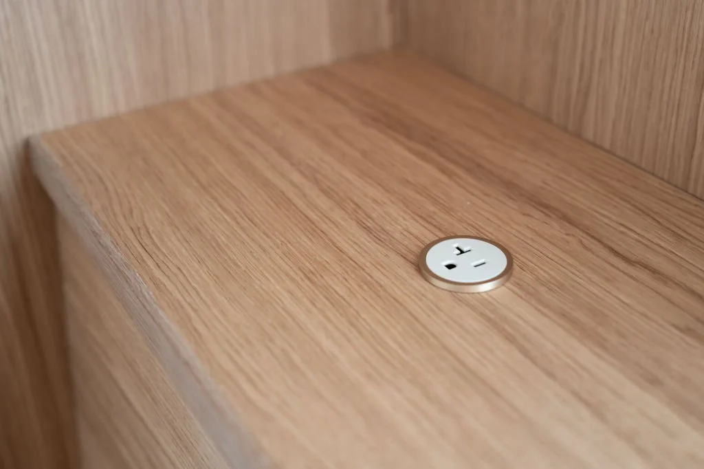 White oak banquette bench detail with integrated Prado power outlet.