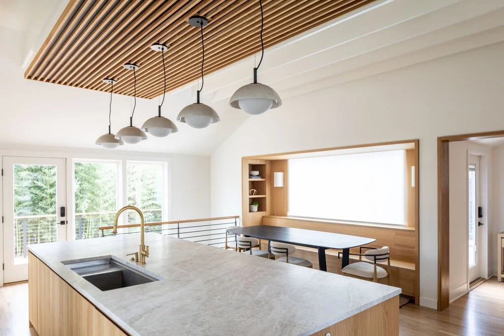 View from kitchen island toward built-in banquette dining framed in white oak with large dining table.