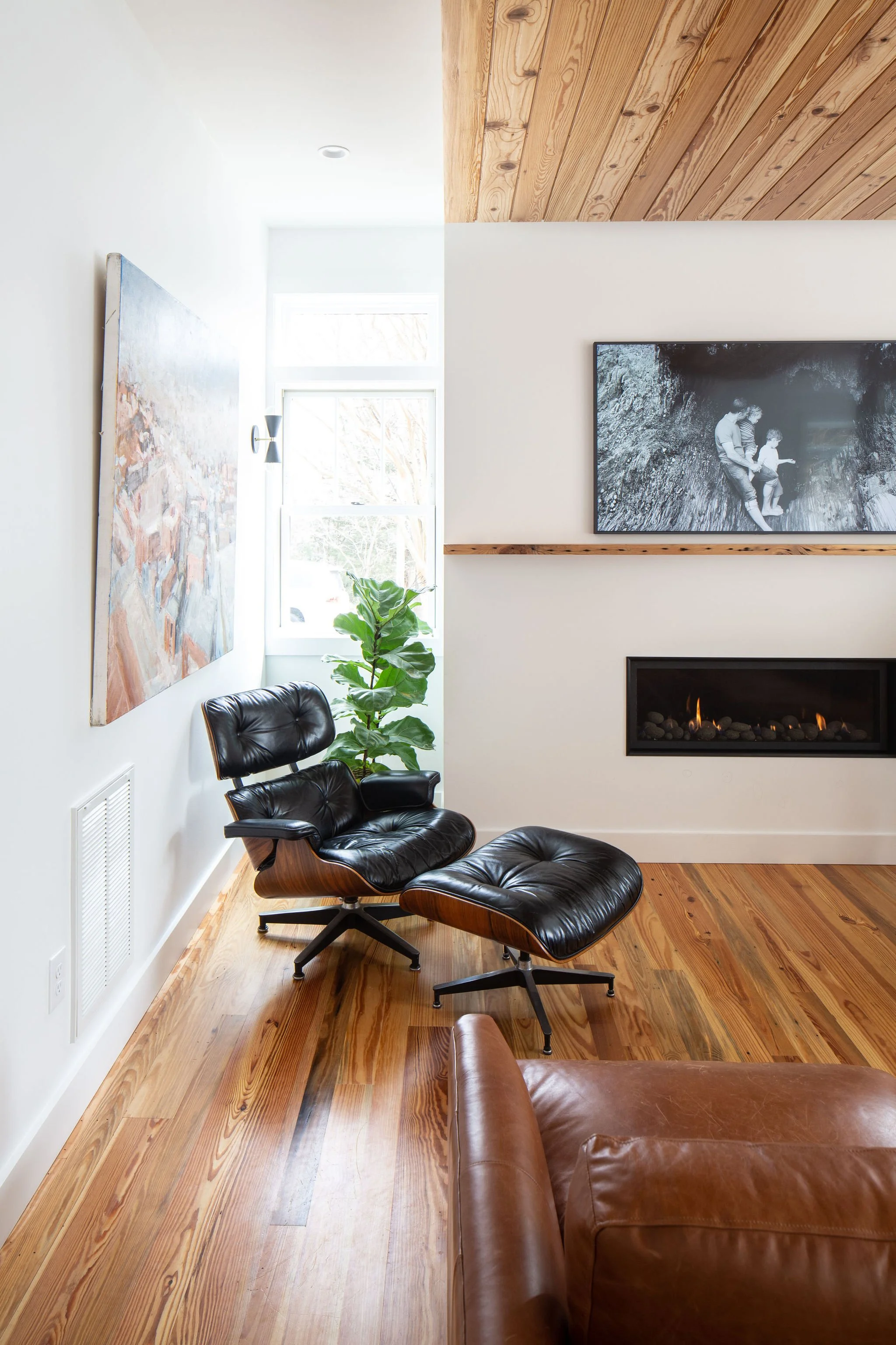 Detail of suspended heart pine ceiling panel meeting fireplace with Eames lounge.