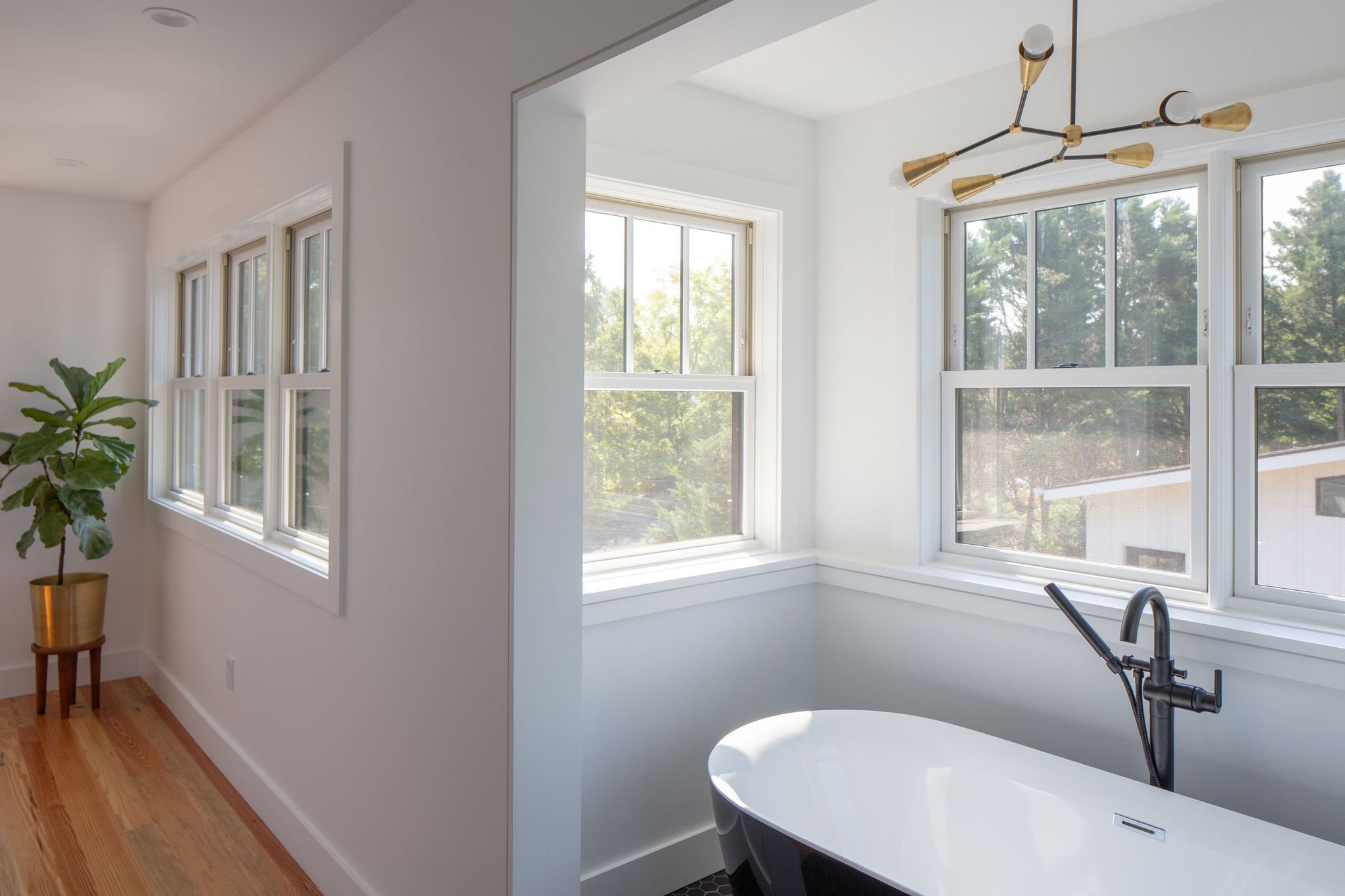 Looking into primary bedroom at mountain views from bathroom with black freestanding tub.