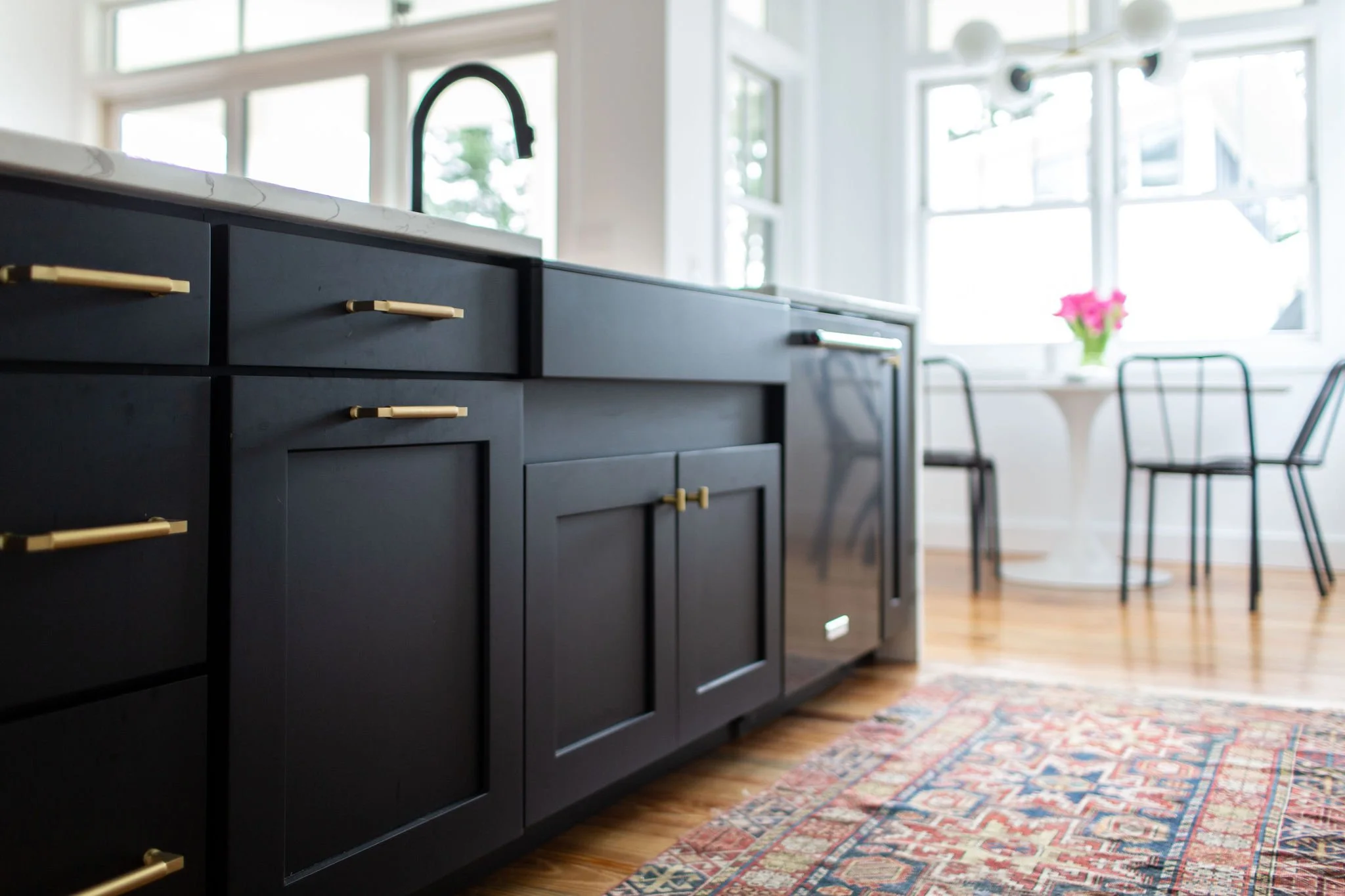 Detail of black shaker style island cabinetry and modern apron front sink.