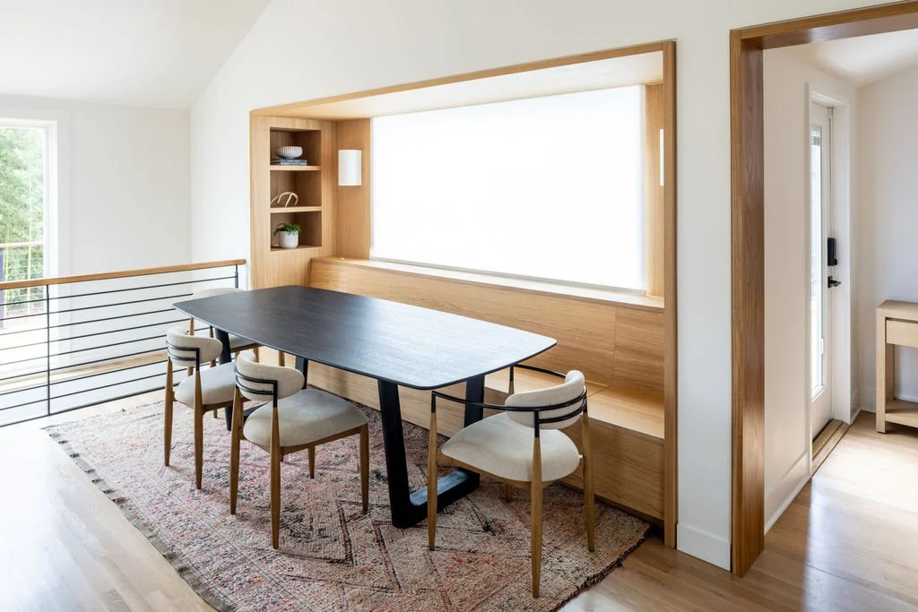 Built-in white oak banquette dining area with large table and integrated shelving.