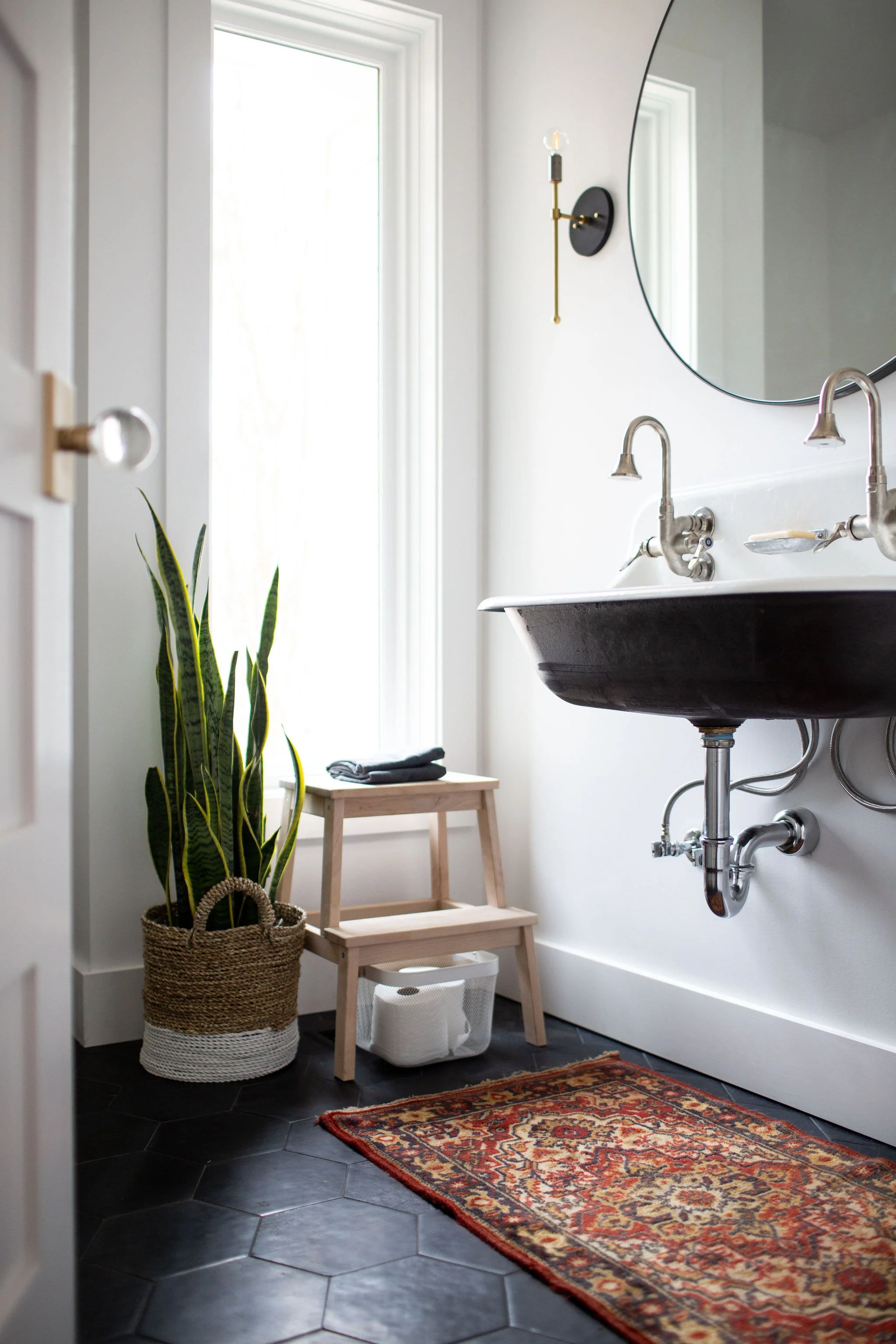 Powder room with floor-to-ceiling window, black hexagonal tile, and wall-hung farmhouse utility sink.