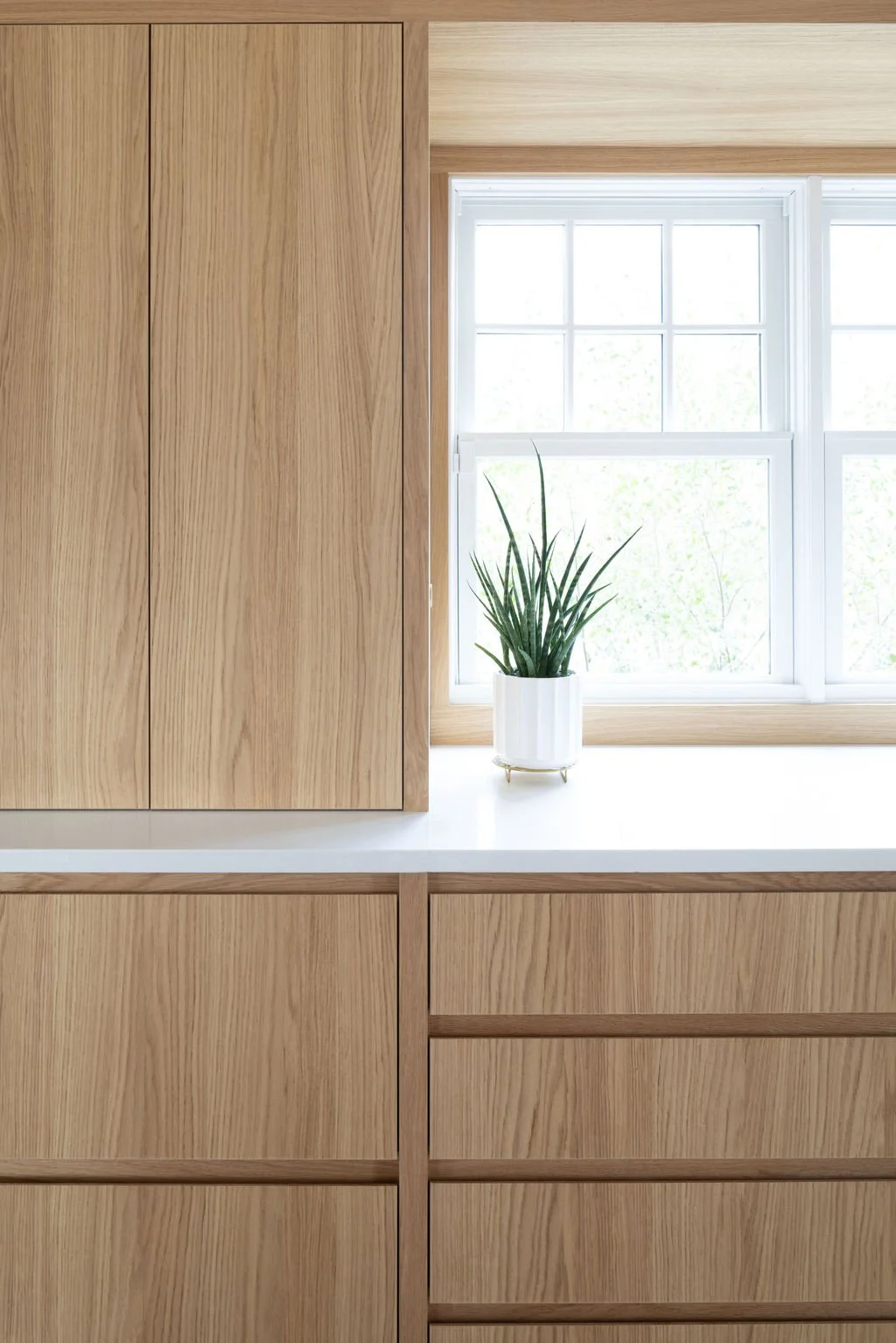 Detail of white oak cabinetry and window trim in modern kitchen renovation.