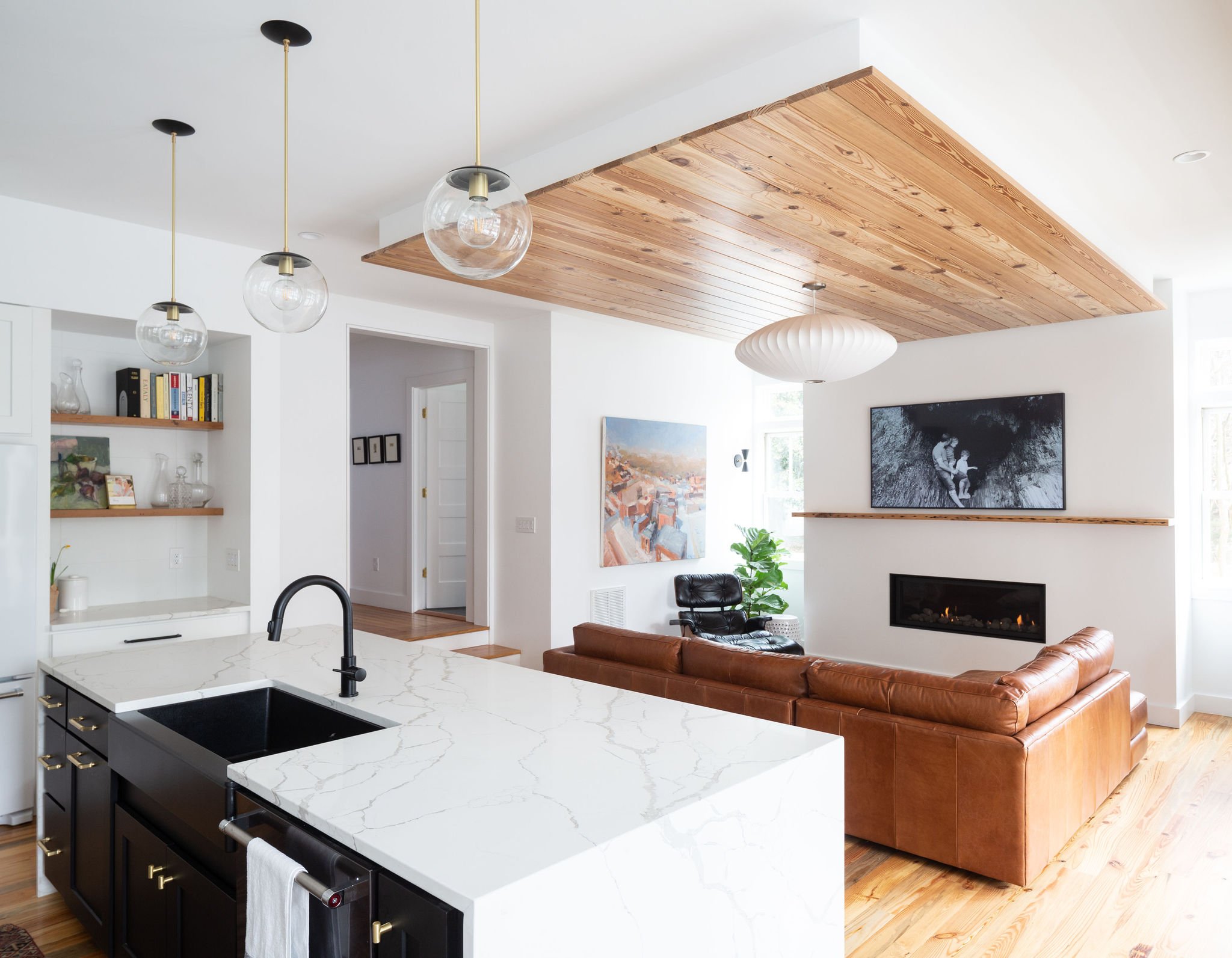 A modern, naturally-lit living room with tall ceilings, modern fireplace, reclaimed heart pine flooring, and suspended ceiling panel of reclaimed heart pine.