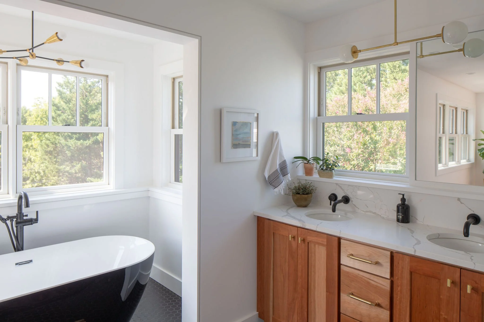Primary bathroom with black freestanding tub surrounded by windows.