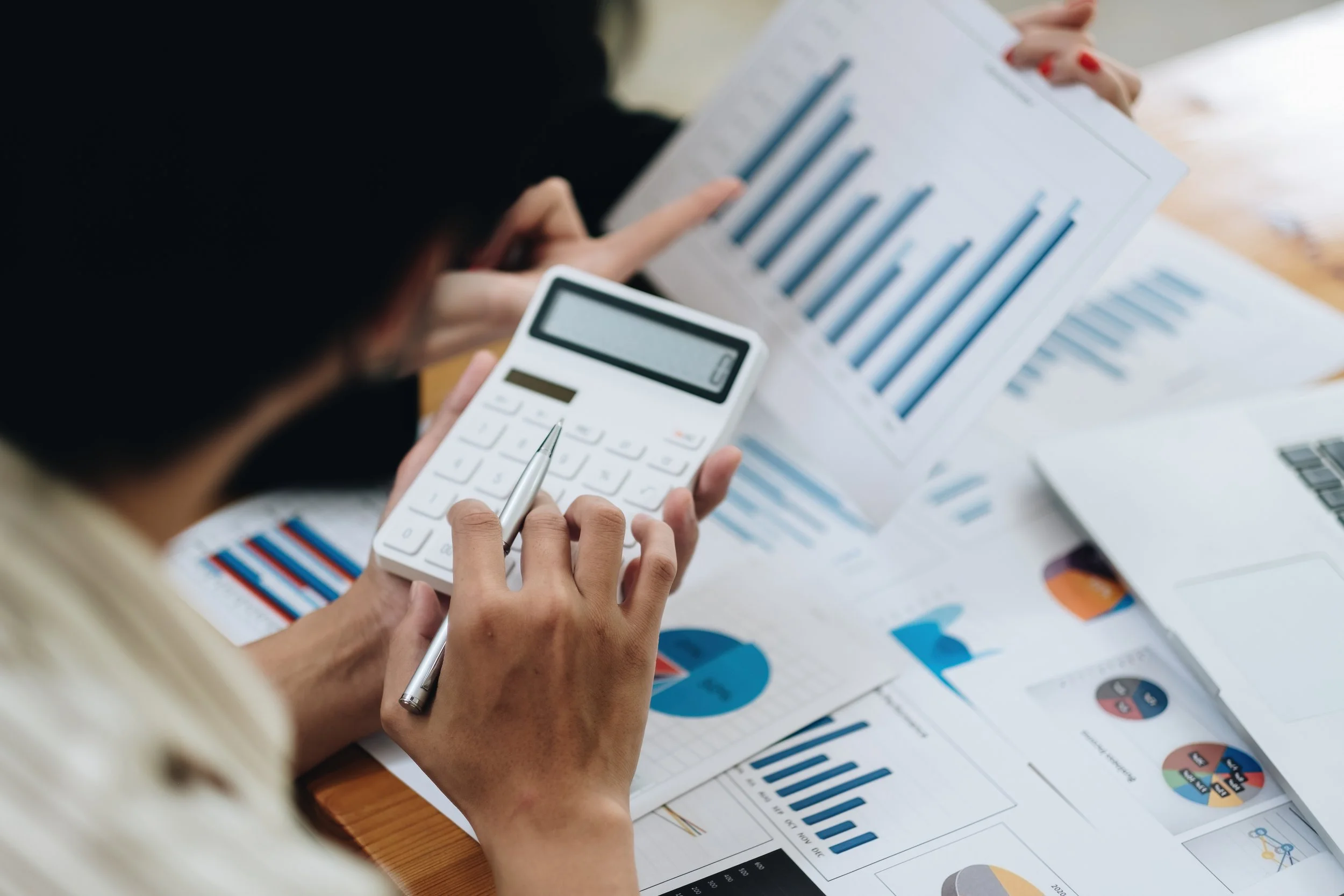 Investor reviewing loan underwriting calculations and financial charts with a calculator