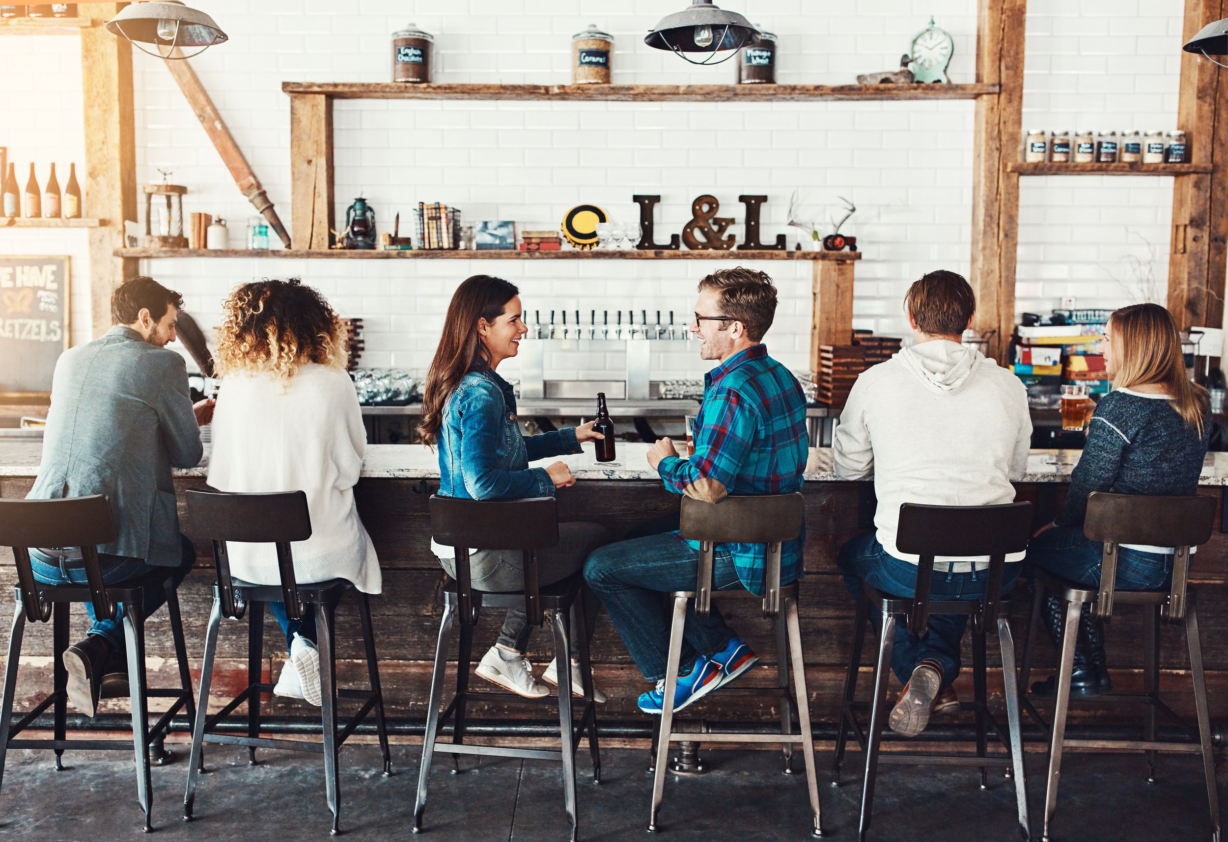 Customers dining at a restaurant bar, representing the food-service tenants driving strip center retail demand