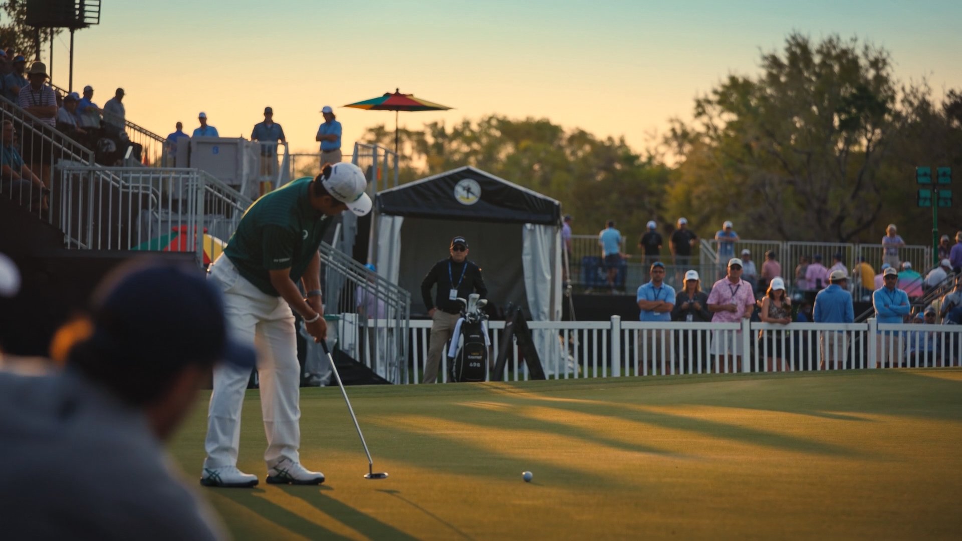 spectators watching a golfer putt