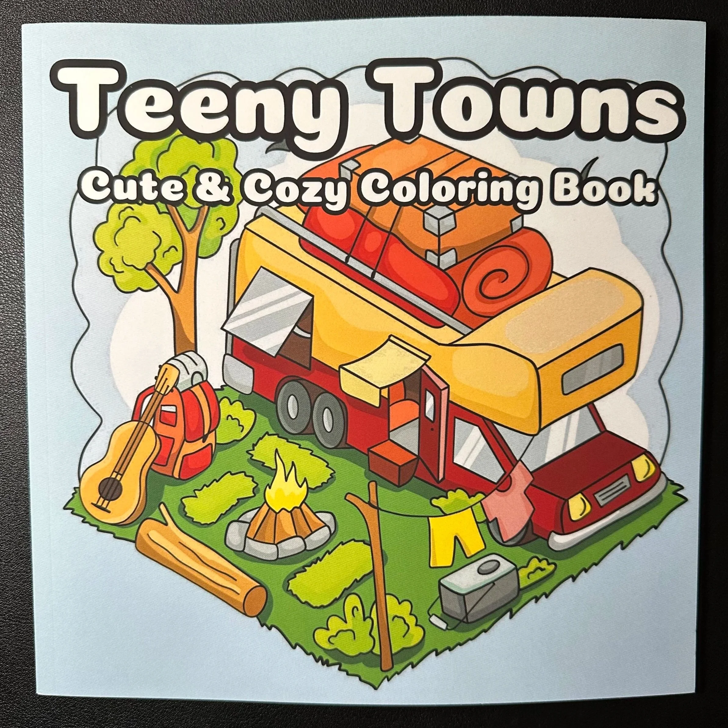 Colorful cartoon illustration of a cozy outdoor scene with a camping trailer, trees, a campfire, and musical instruments, with text that reads "Jeepiy Tourns" and "Cute & Cozy Coloring Book."