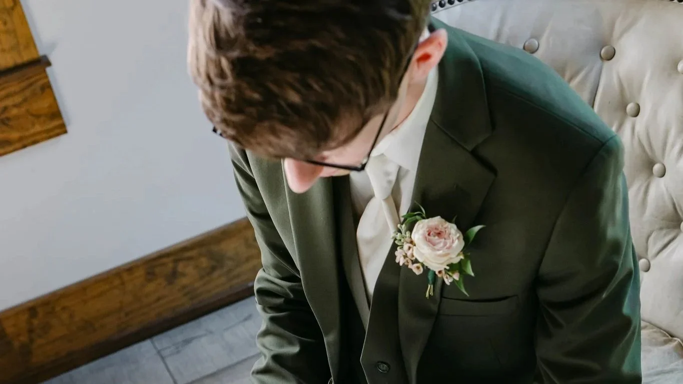 Classic bout with pink spray rose and accented with wax flower.