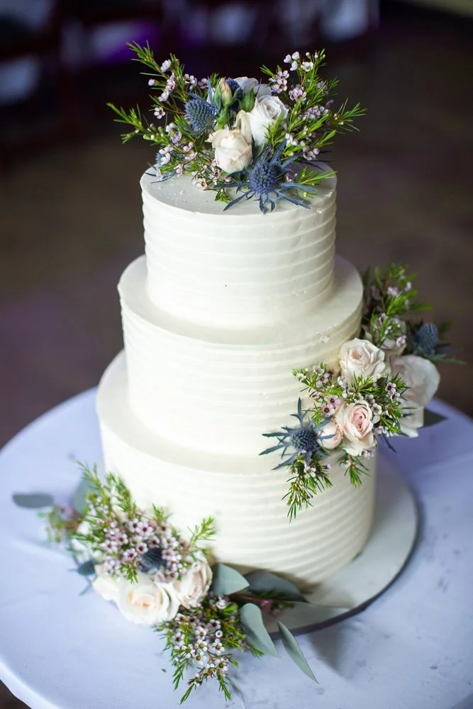 Three-tiered white wedding cake with floral decorations.