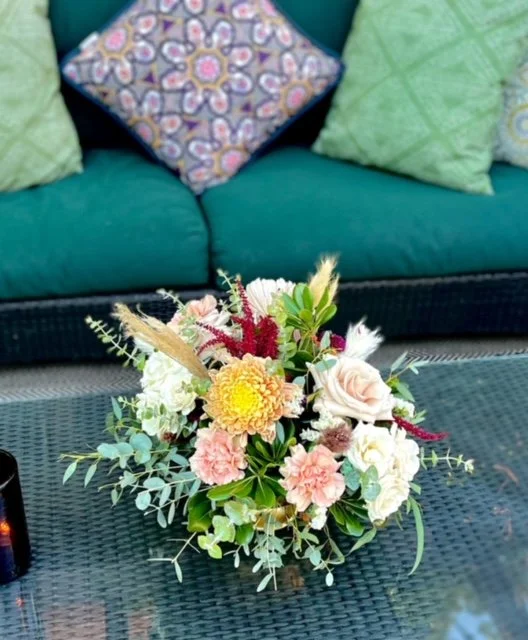 Floral arrangement on a wicker table with decorative pillows