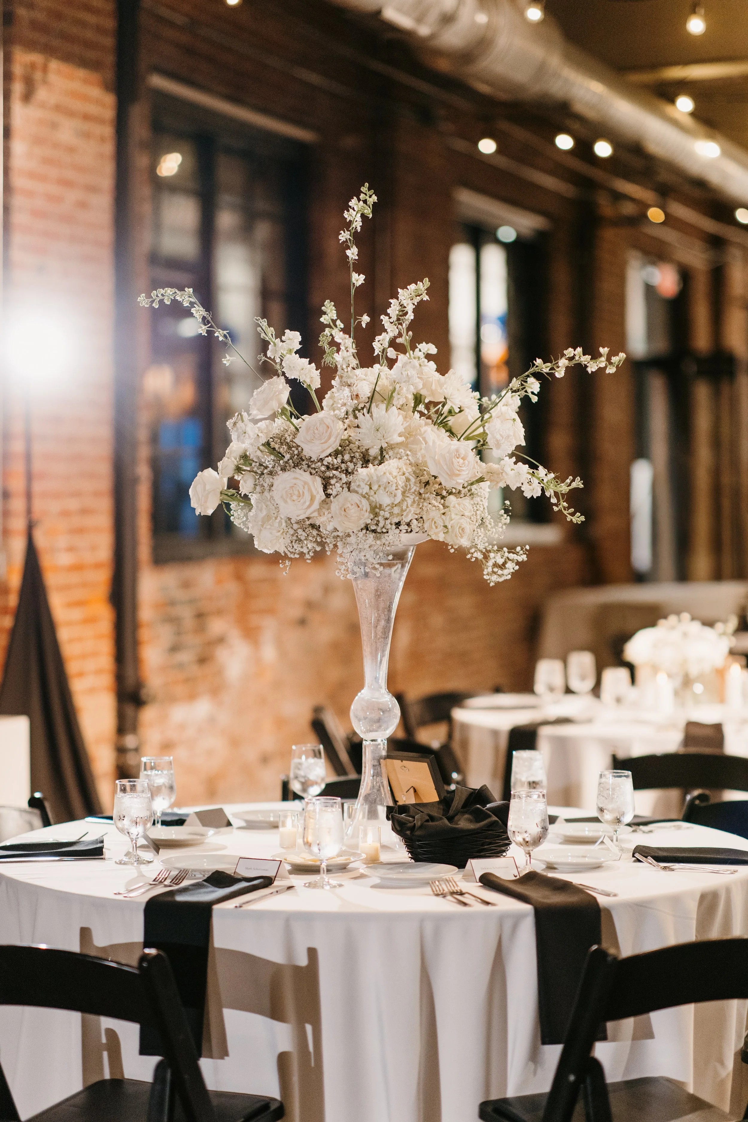 Repurposed altar arrangement to tall stand for wedding reception for an elegant modern feel.