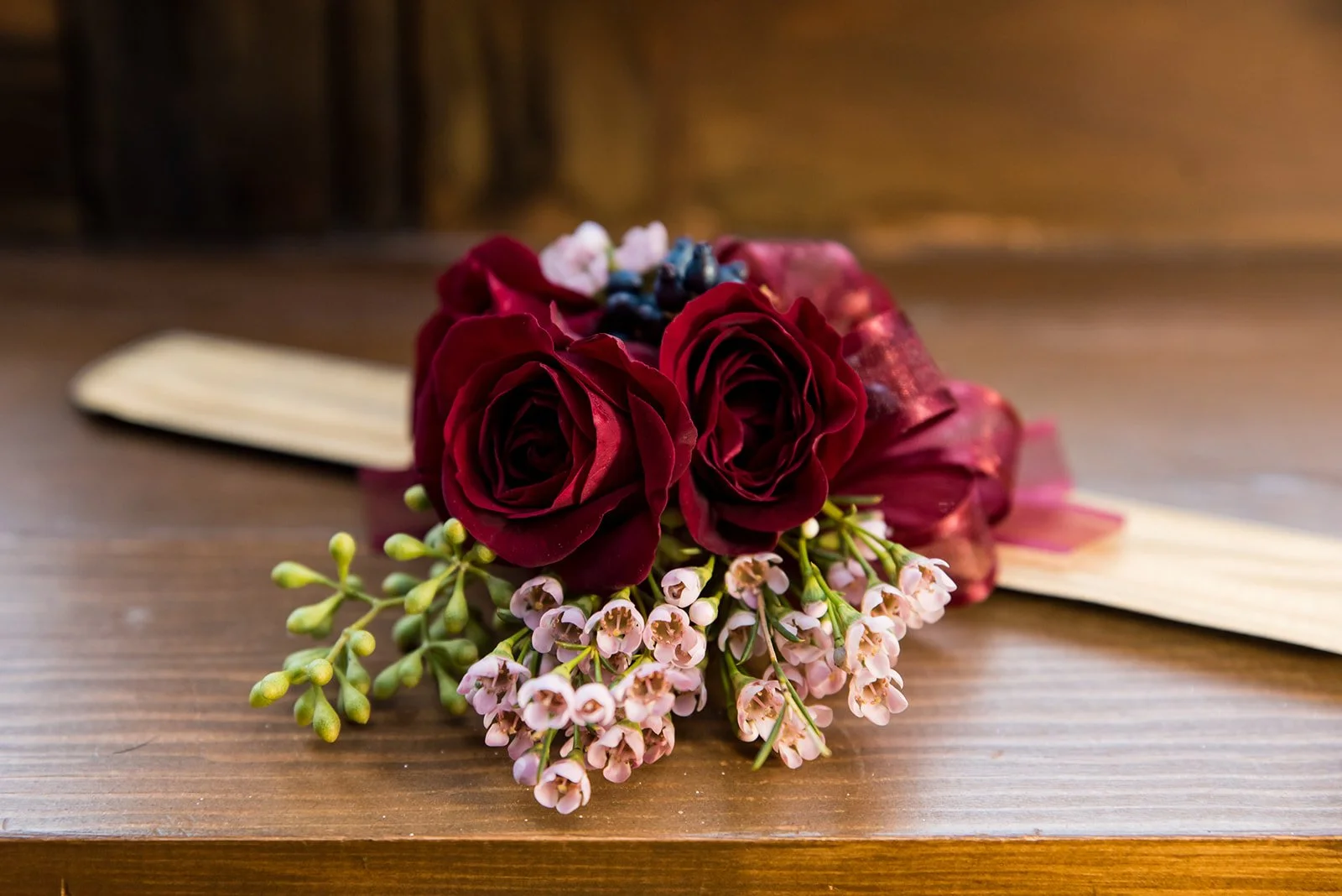 Red roses with pink flowers and green buds on wooden background.