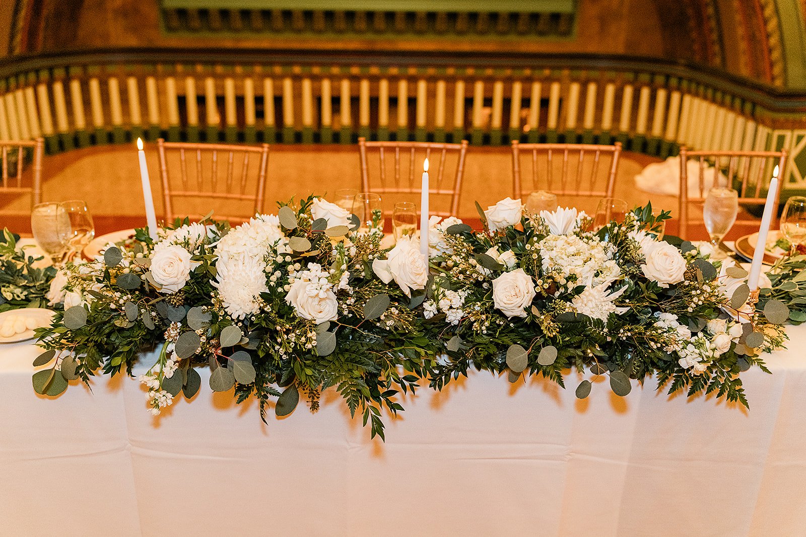 Head table swag in greens with white blooms.