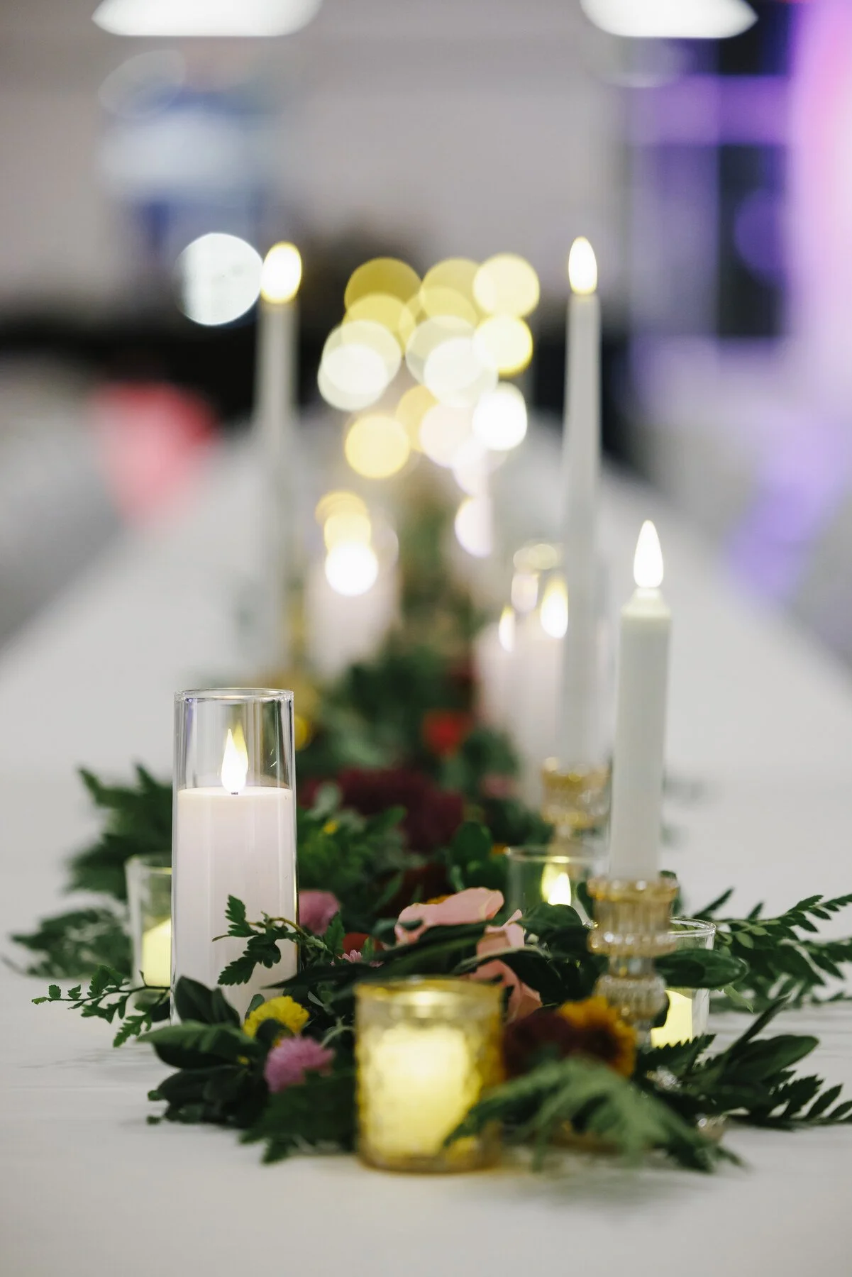 A table with lit candles and floral centerpieces