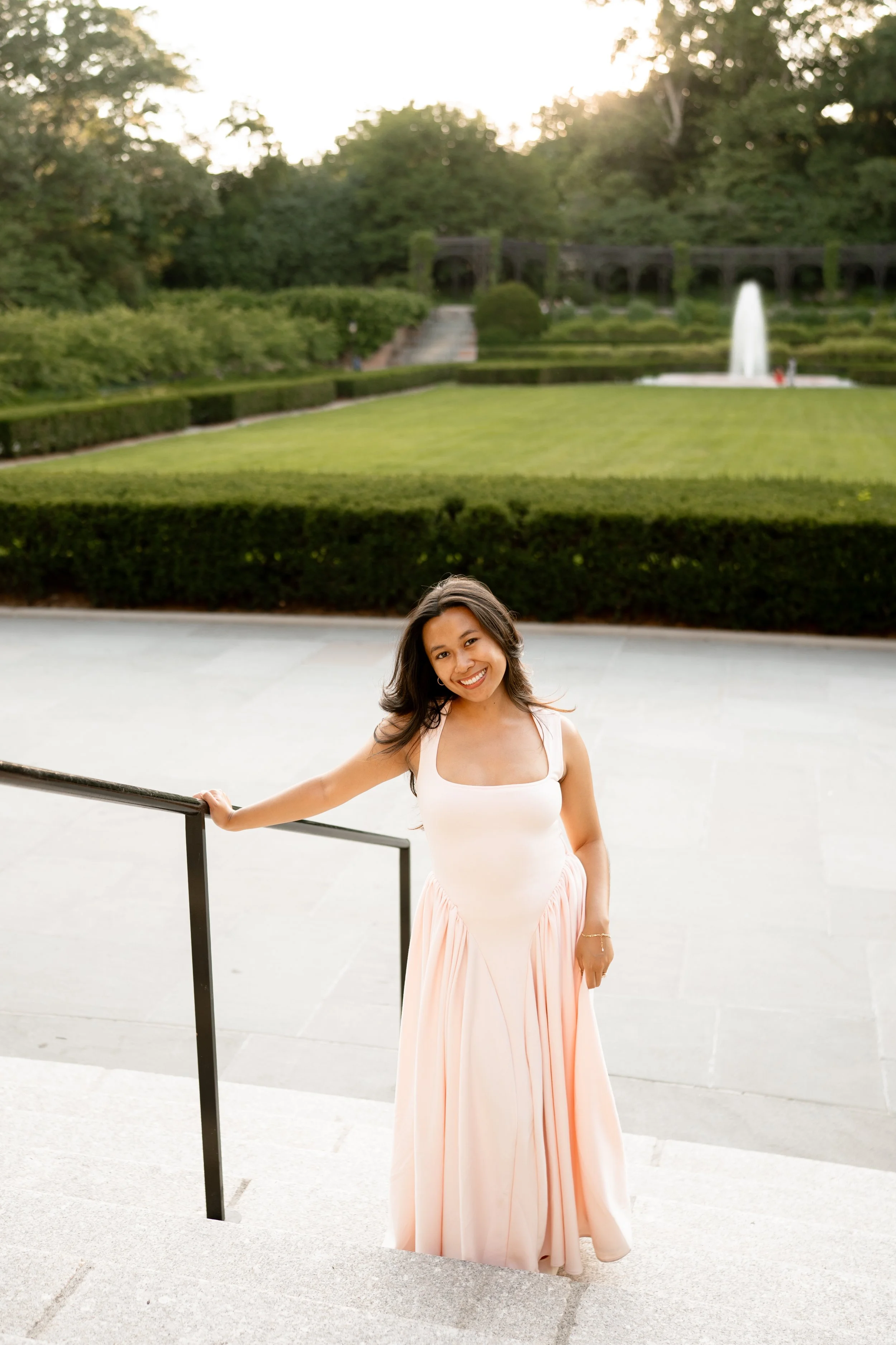 Calista Hennie, standing on a staircase in front of a meadow in Central Park.