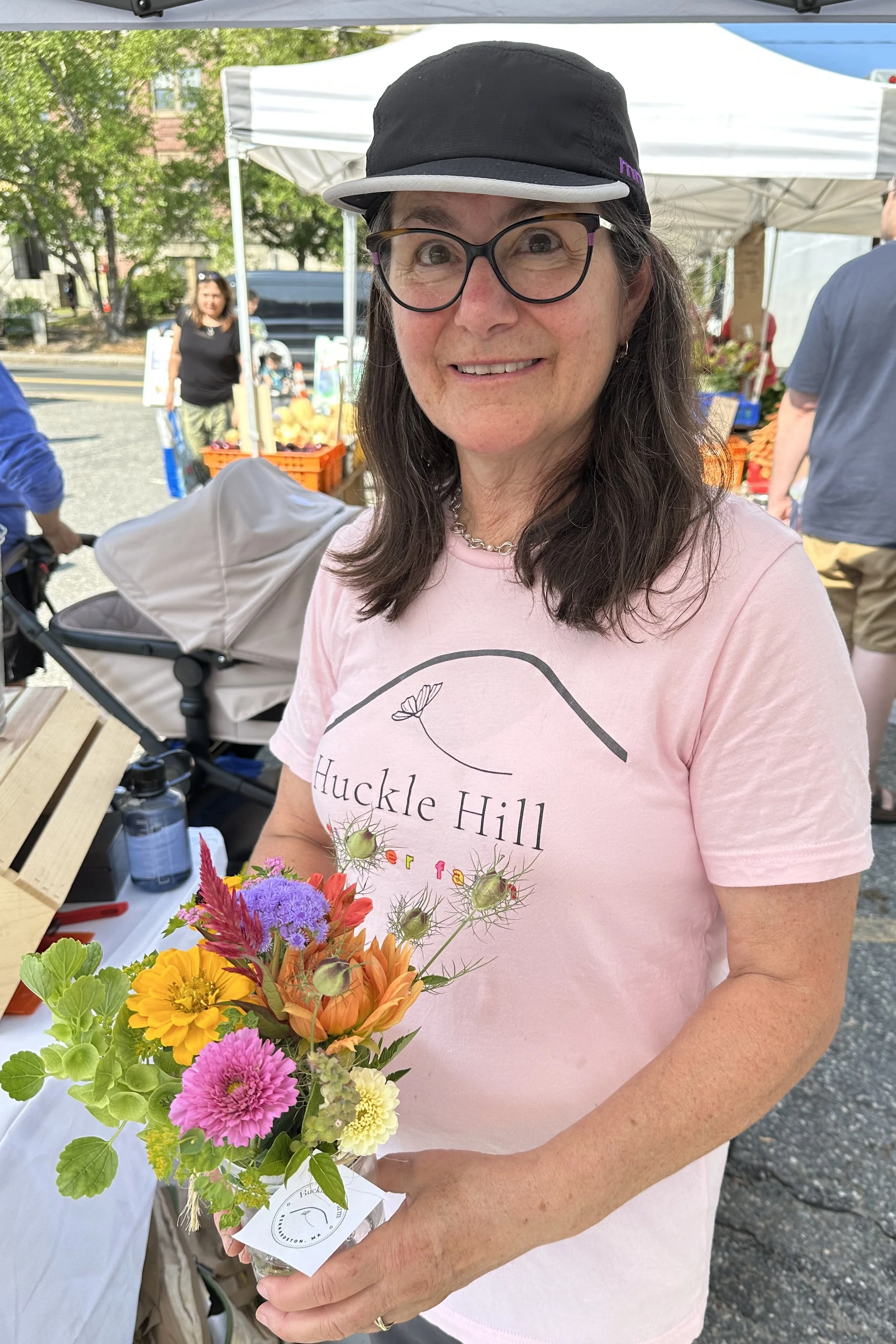 Head Petal Picker Pam holding mason jar bouquet at Farmers' Market.