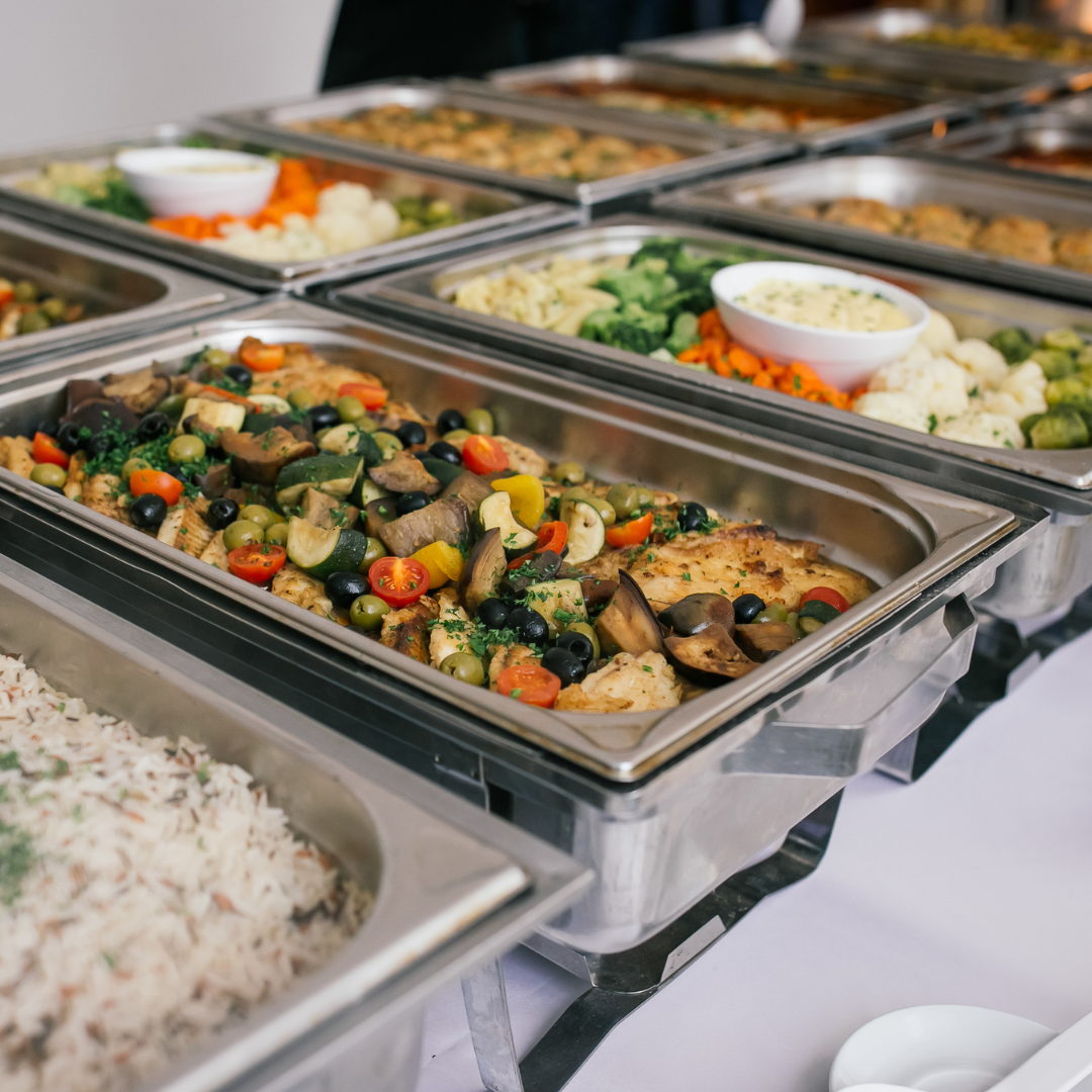 Buffet style catering with assorted trays of salads, vegetables, and rice dishes.