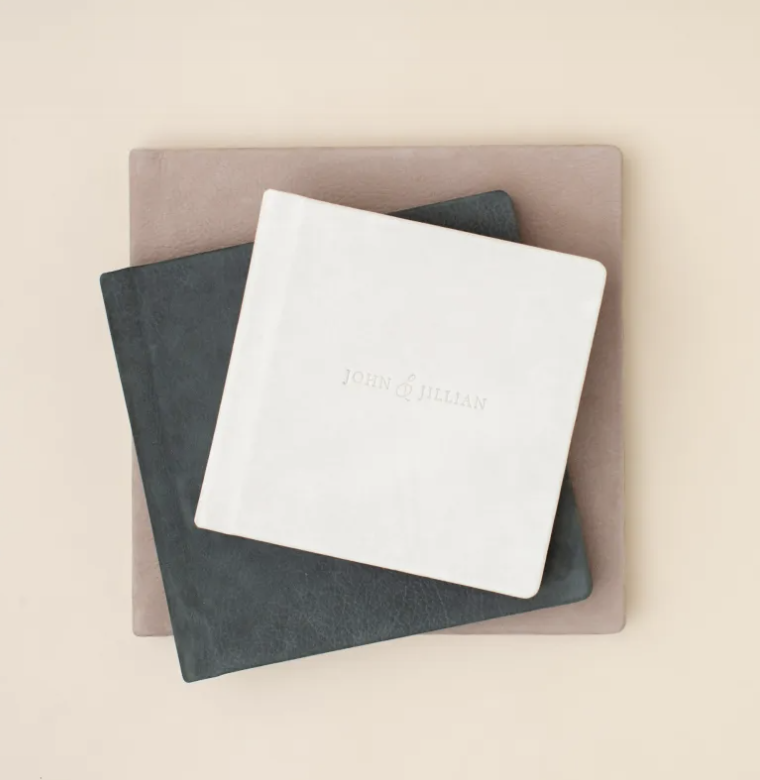 Three stacked photo albums on a beige background, with the top one labeled "John & Jillian."