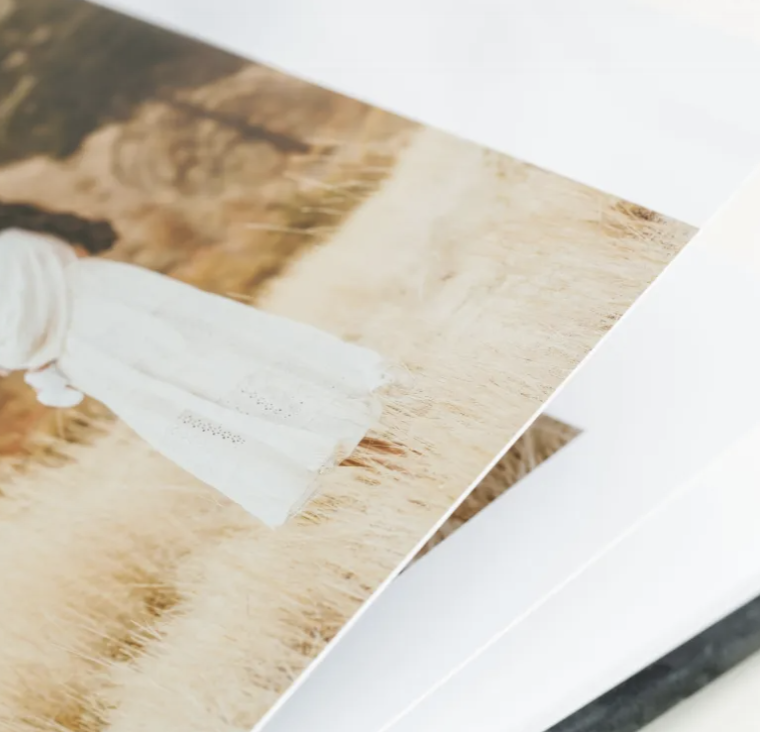 Close-up of a printed photograph featuring a person in a white dress standing in a field of wheat.