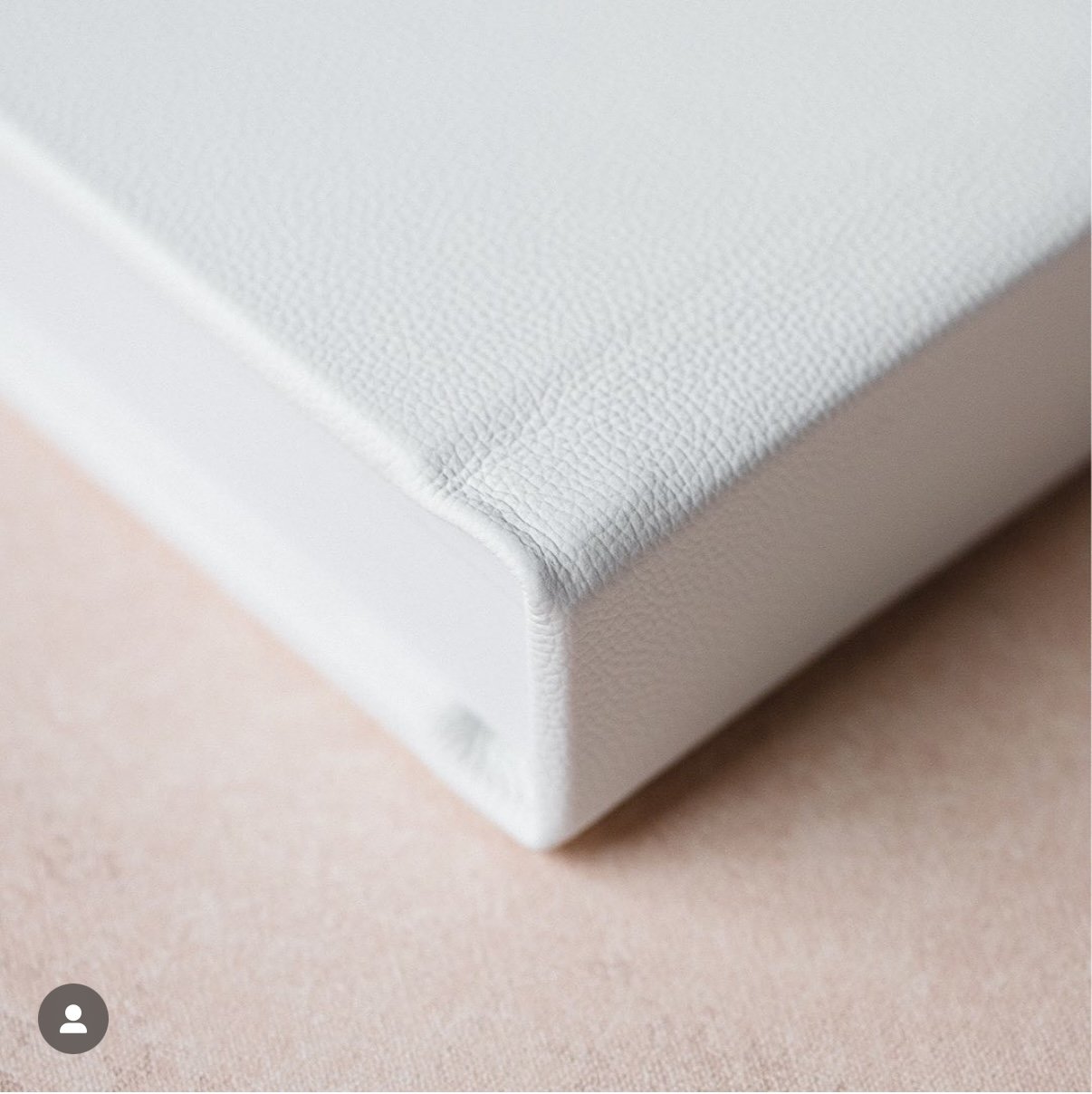 Close-up of white leather-bound book on a beige surface