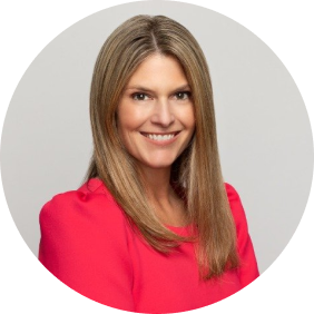 A smiling woman with long, straight blonde hair wearing a bright pink blazer against a light, neutral background.