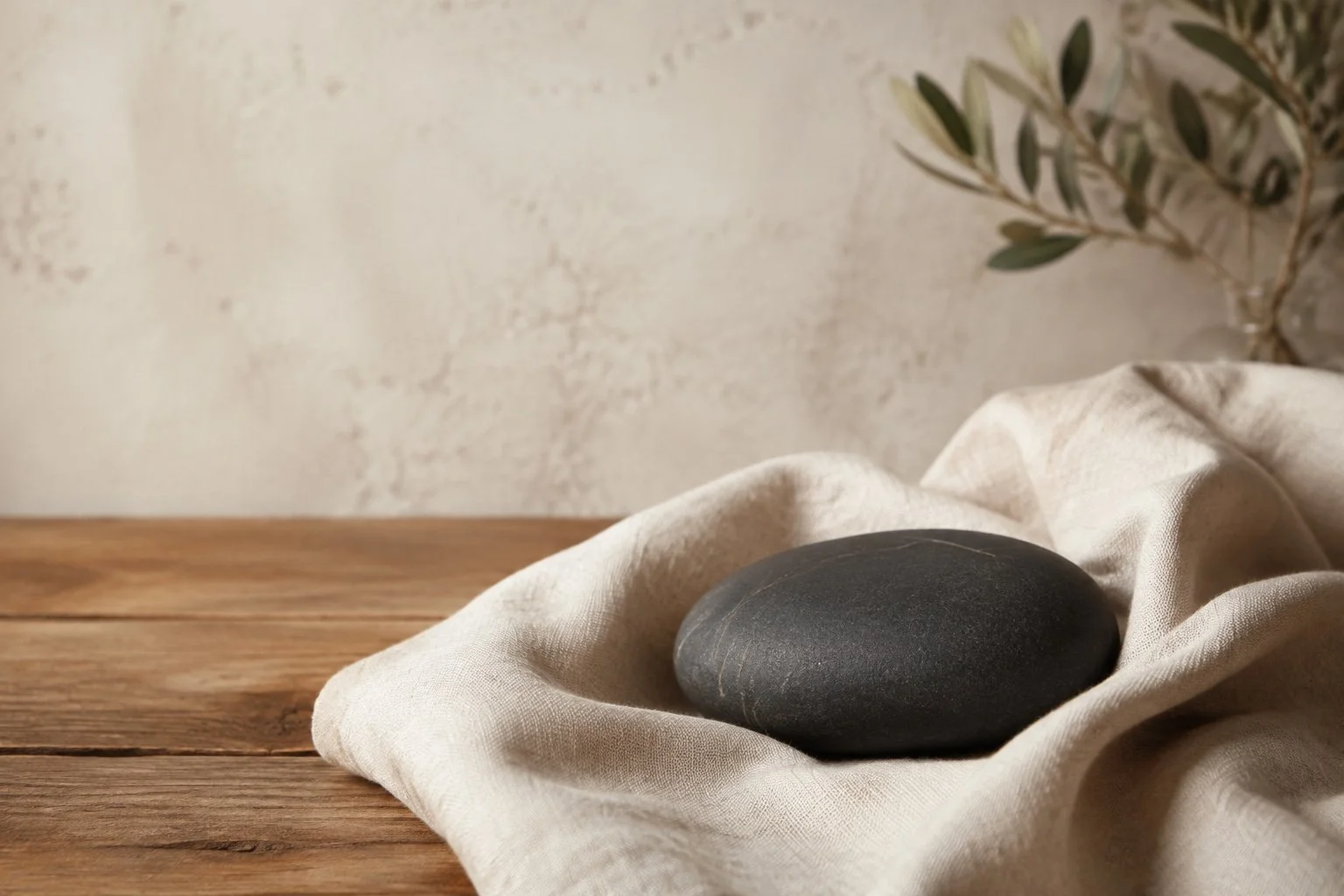 Piedra oscura sostenida por un paño de lino sobre una mesa de madera.