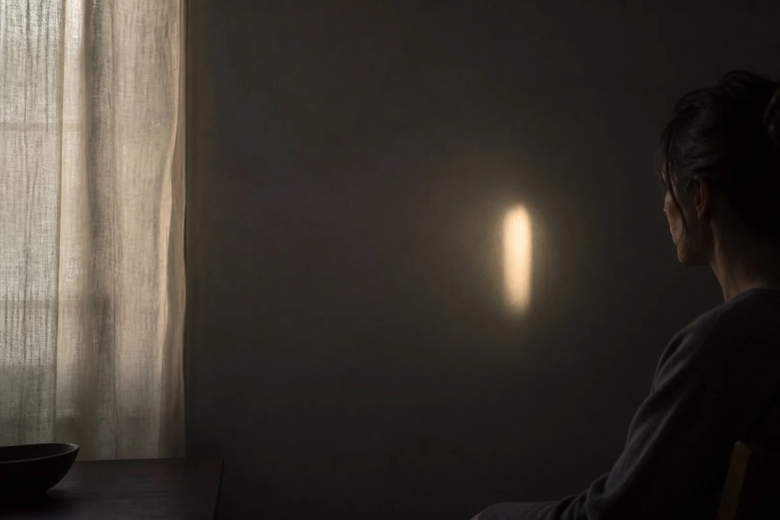 Persona situada en sombra mirando un único punto de luz en la pared