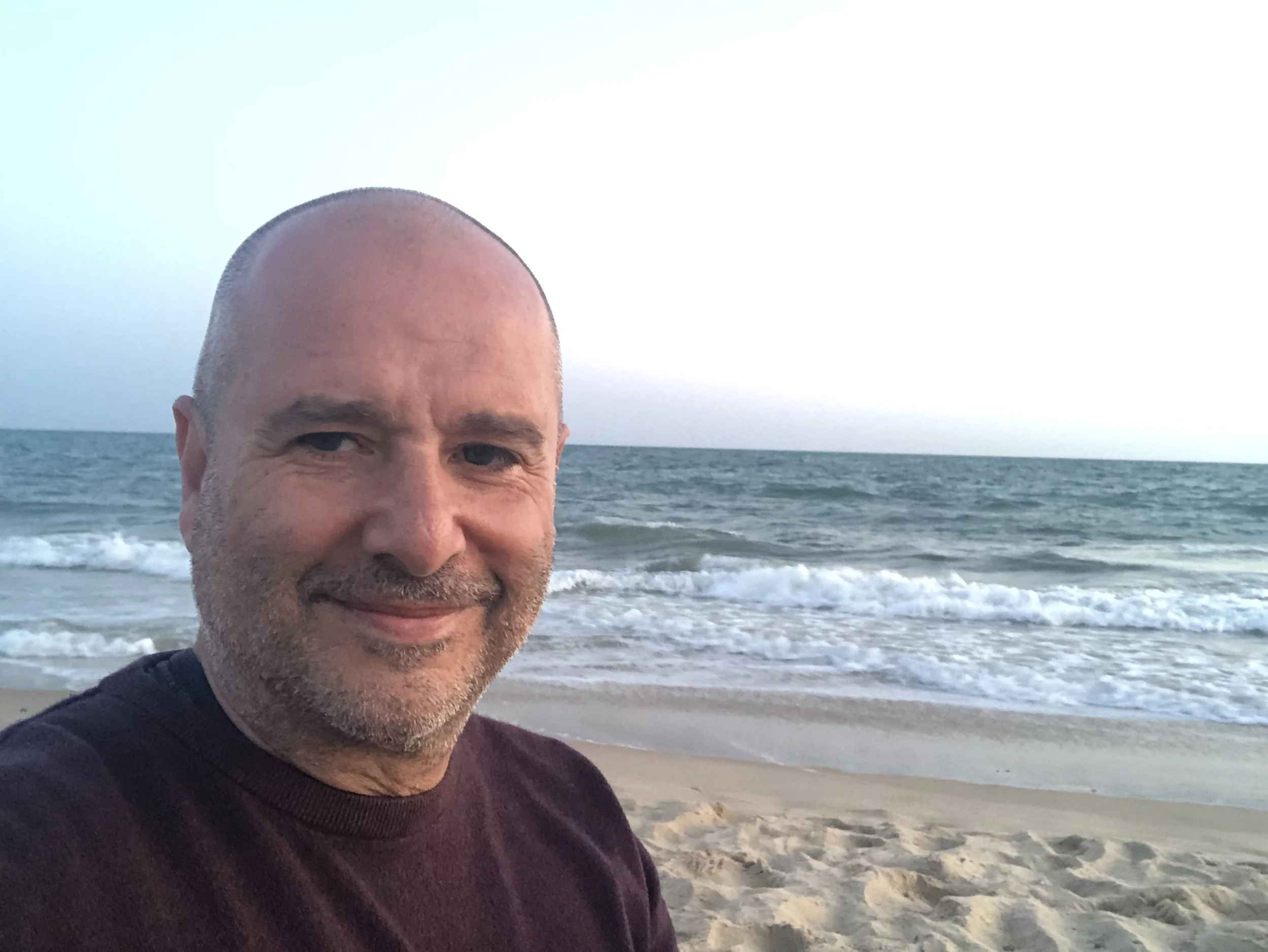 Rafael Guisado sonriendo en una playa, con el mar al fondo.
