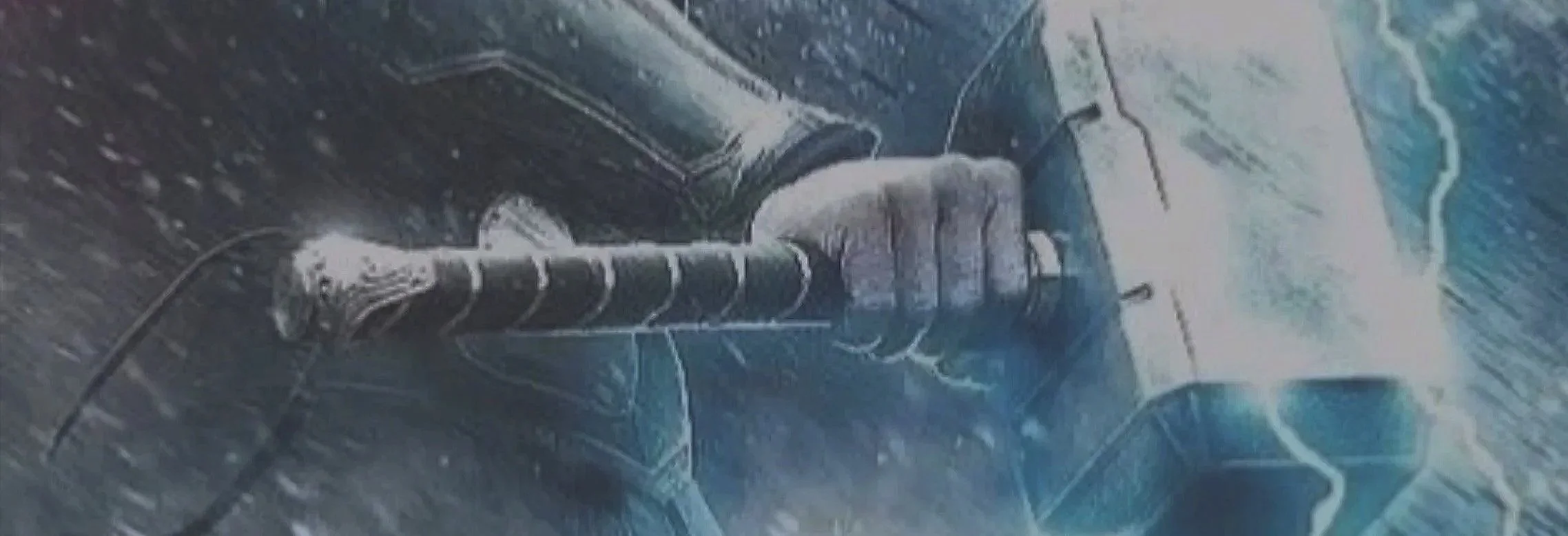 Close-up of a hand grasping a metallic object with wires and attachments, with rain falling and a blurred background.