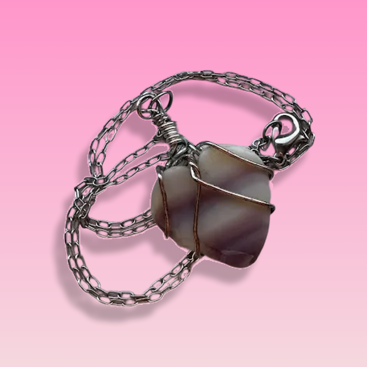 A silver chain necklace with a large, irregularly shaped pearl pendant on a pink background.