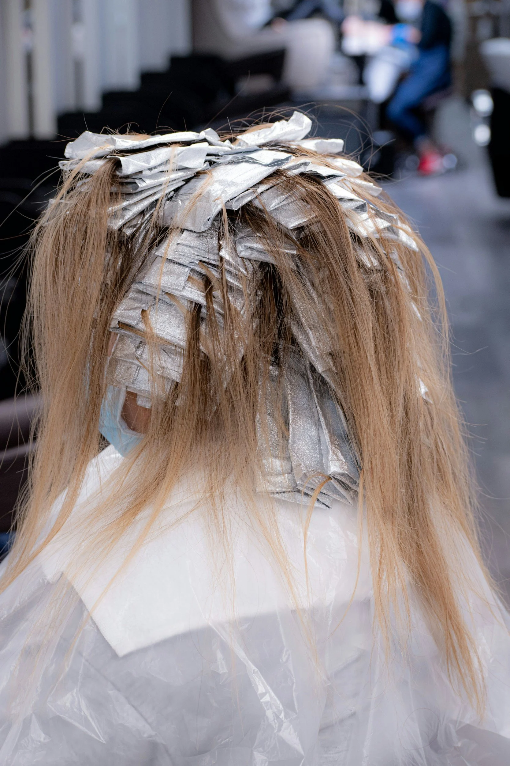 Person getting hair highlighted with foil at a salon.