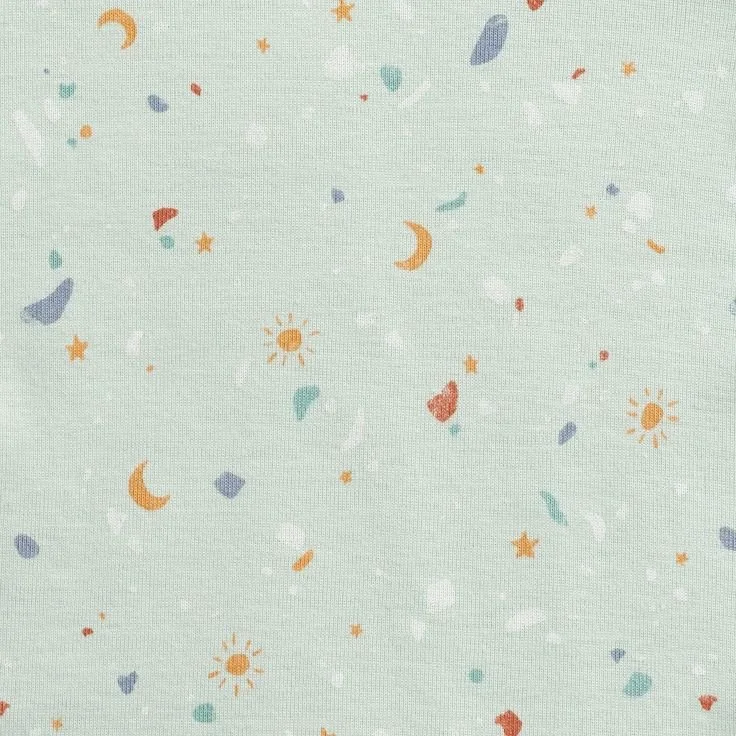 Light green fabric with small colorful celestial and abstract shapes, including suns, moons, stars, and various blobs in orange, blue, red, white, and teal.