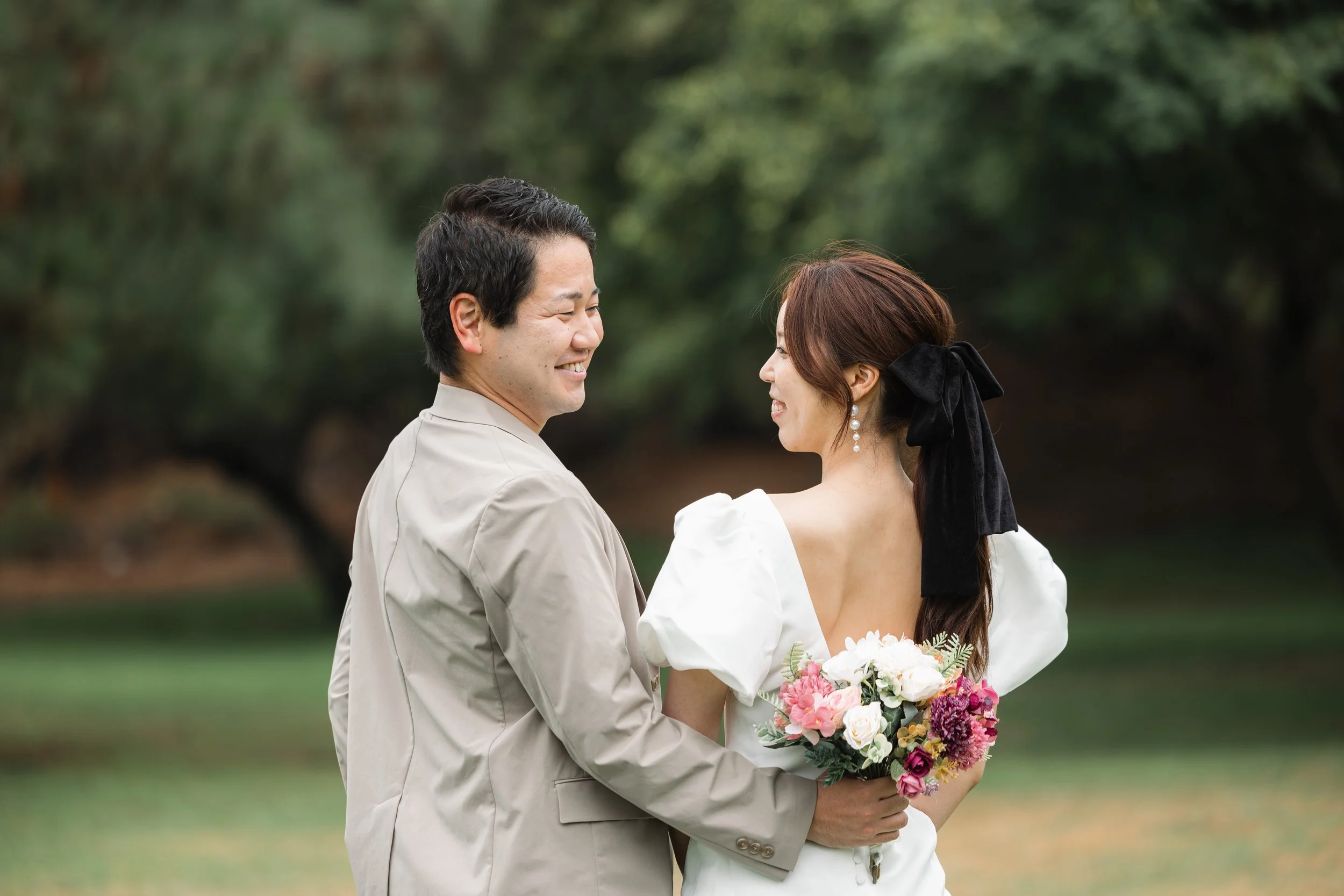 結婚式の衣装を着たカップルが自然の中で微笑み合っている